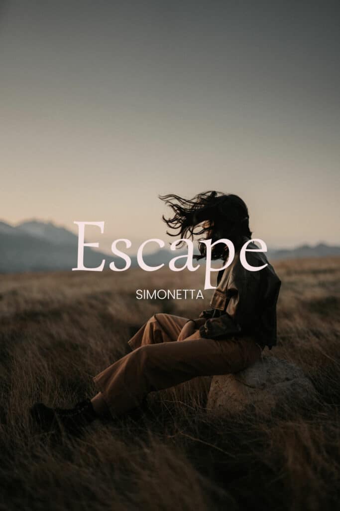 shows the word 'Escape' written in Simonetta Font - a lightweight display boho font with a windswept woman on a mountain landscape in the background