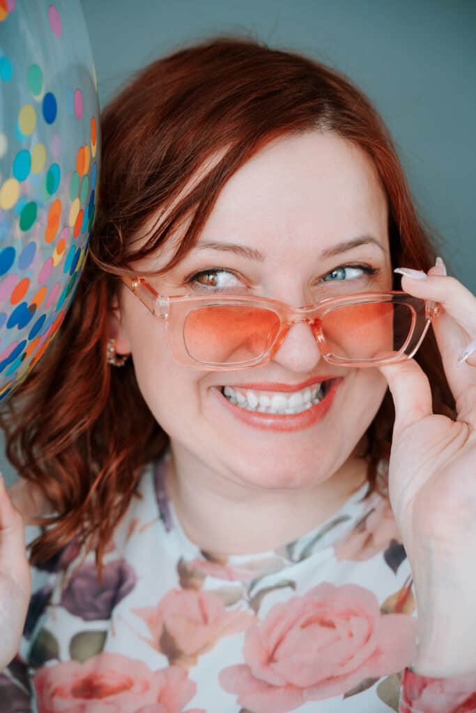 Photo of brand photographer, Inese, wearing fun pink tinted sunglasses smiling after her rebrand