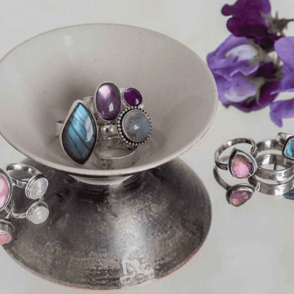 gemstone rings in a bowl with purple flowers in the background