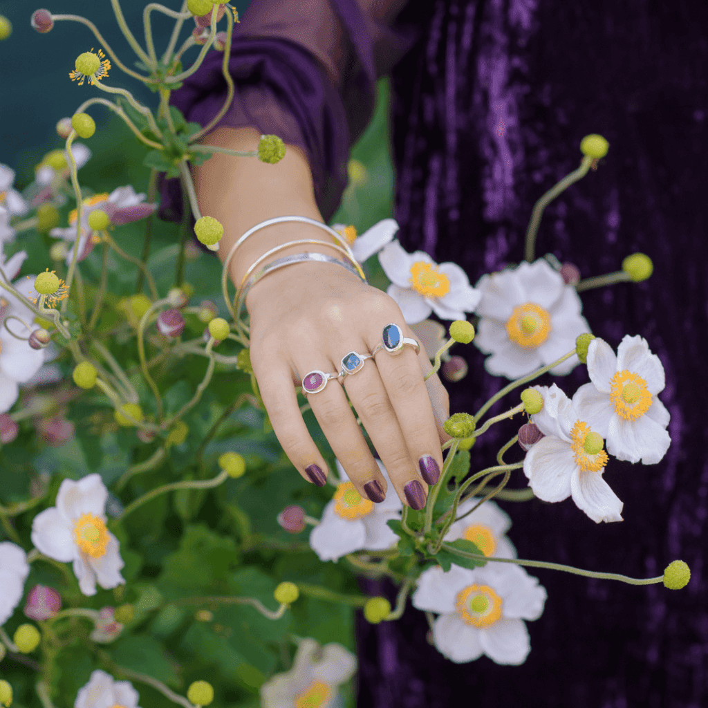 woman in garden wearing different colour Laura De Zordo rings