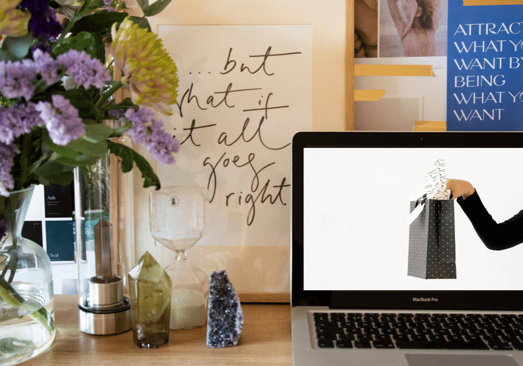 Desk with flowers, crystals and a laptop showing Girl Boss gift guide blog post