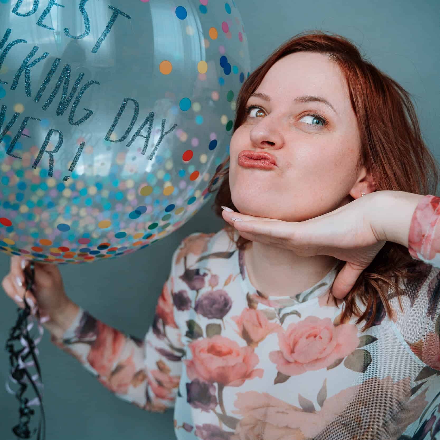 Photo of brand photographer, Inese, holding a confetti balloon that says best fucking day ever!